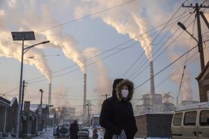 SHANXI, CHINA -NOVEMBER 26: (CHINA, HONG KONG, MACAU, TAIWAN OUT) Smoke billows from stacks as a Chinese woman wears as mask while walking in a neighborhood next to a coal fired power plant on November 26, 2015 in Shanxi, China. A history of heavy dependence on burning coal for energy has made China the source of nearly a third of the world's total carbon dioxide (CO2) emissions, the toxic pollutants widely cited by scientists and environmentalists as the primary cause of global warming. China's government has publicly set 2030 as a deadline to reach the country's emissions peak, and data suggest the country's coal consumption is already in decline. The governments of more than 190 countries are expected to sign an agreement in Paris to set targets on reducing carbon emissions in an attempt to forge a new global agreement on climate change. (Photo by Kevin Frayer/Getty Images)